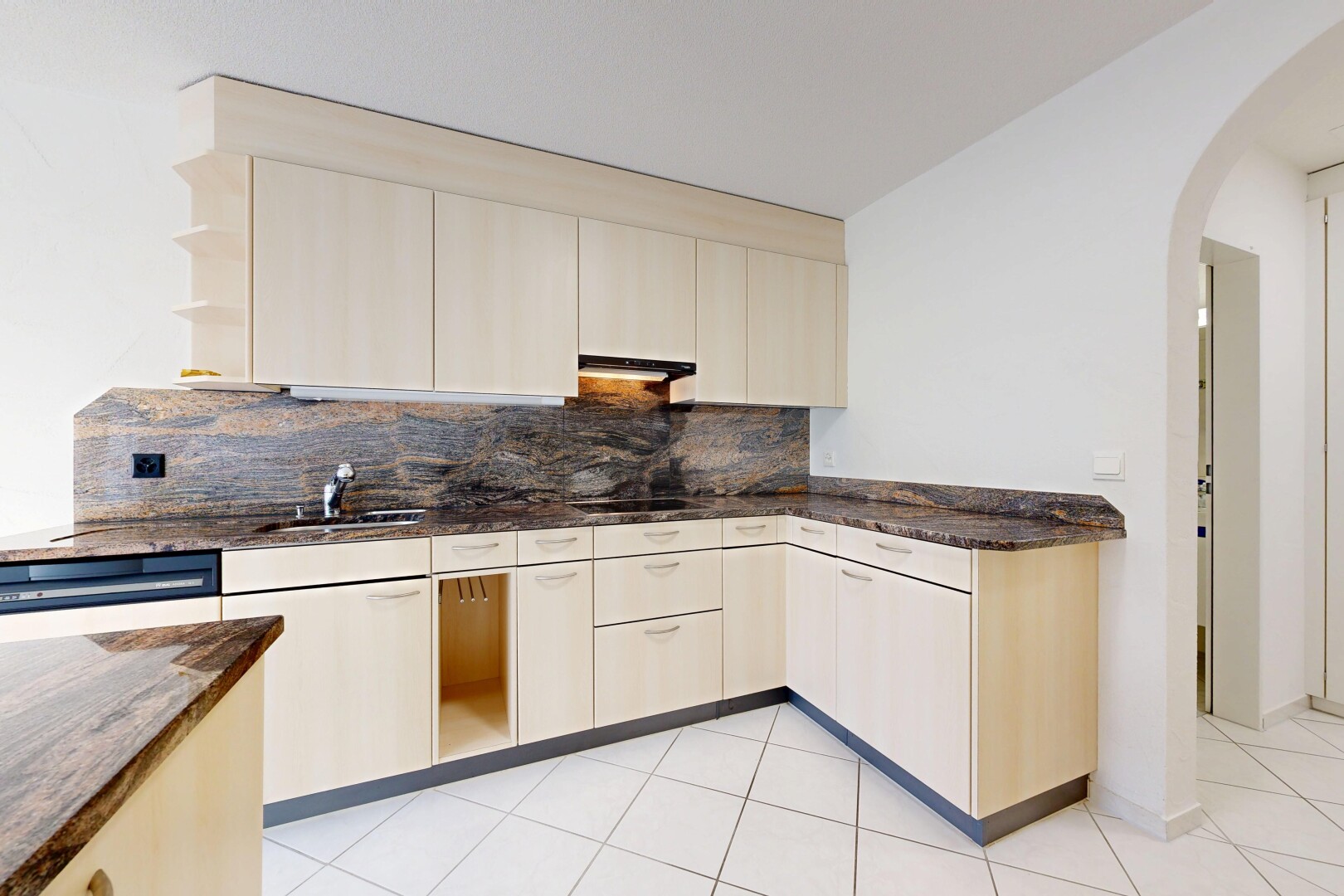 cuisine avec dark countertops, passages en arc, stone countertops, plans de travail en pierre, et drywall