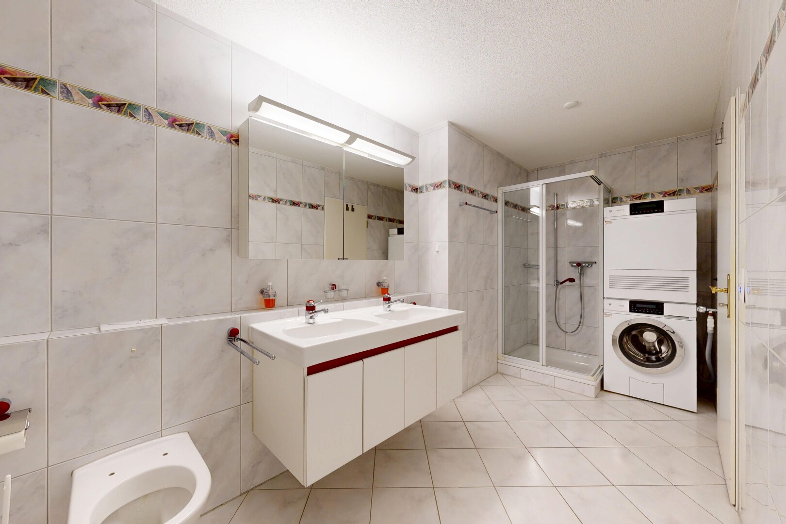 salle de bains avec mur en carrelage, tile wall, double vasque, light floor, et salle de bain complète