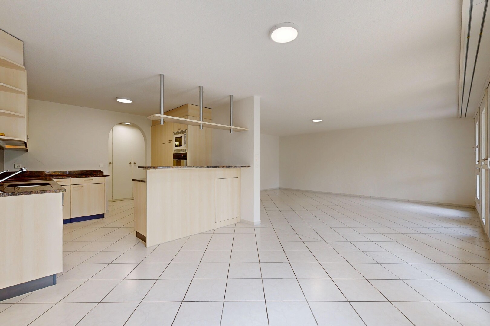 cuisine avec plans de travail, dark countertops, passages en arc, light floor, et inside property