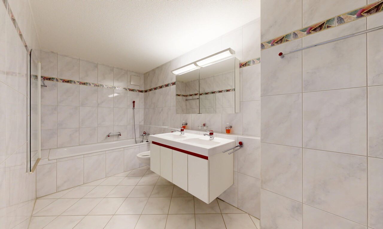 salle de bains avec salle de bain complète, double vasque, light floor, miroir, et mur en carrelage