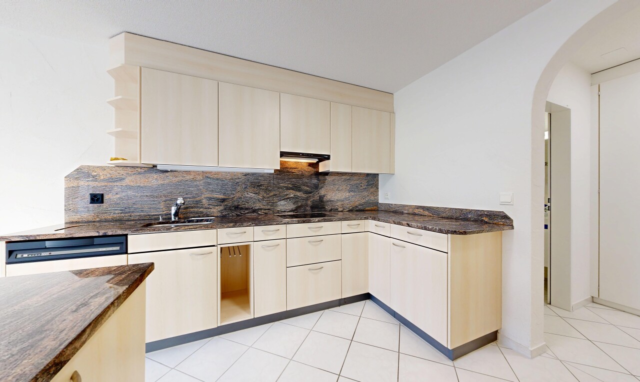 cuisine avec dark countertops, passages en arc, stone countertops, plans de travail en pierre, et drywall