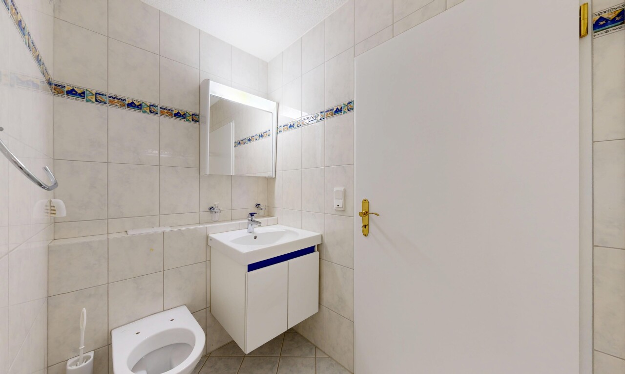 salle de bains avec mur en carrelage, tile wall, lavabo (ou coiffeuse selon le contexte), light floor, et miroir