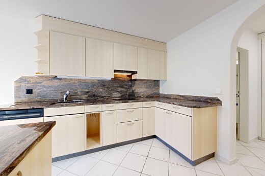 cuisine avec dark countertops, passages en arc, stone countertops, plans de travail en pierre, et drywall