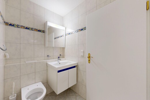 salle de bains avec mur en carrelage, tile wall, lavabo (ou coiffeuse selon le contexte), light floor, et miroir