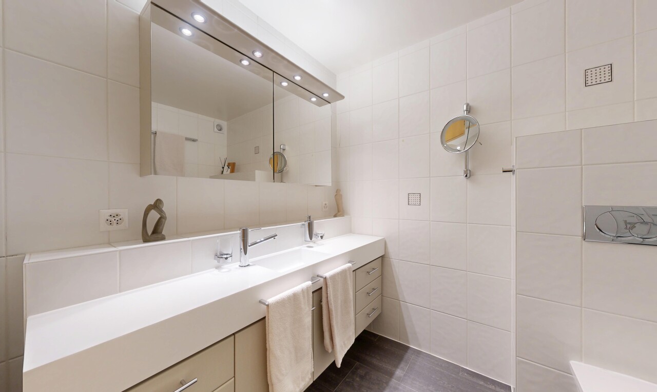 salle de bains avec lavabo (ou coiffeuse selon le contexte), mur en carrelage, tile wall, dark floor, et salle de bain complète