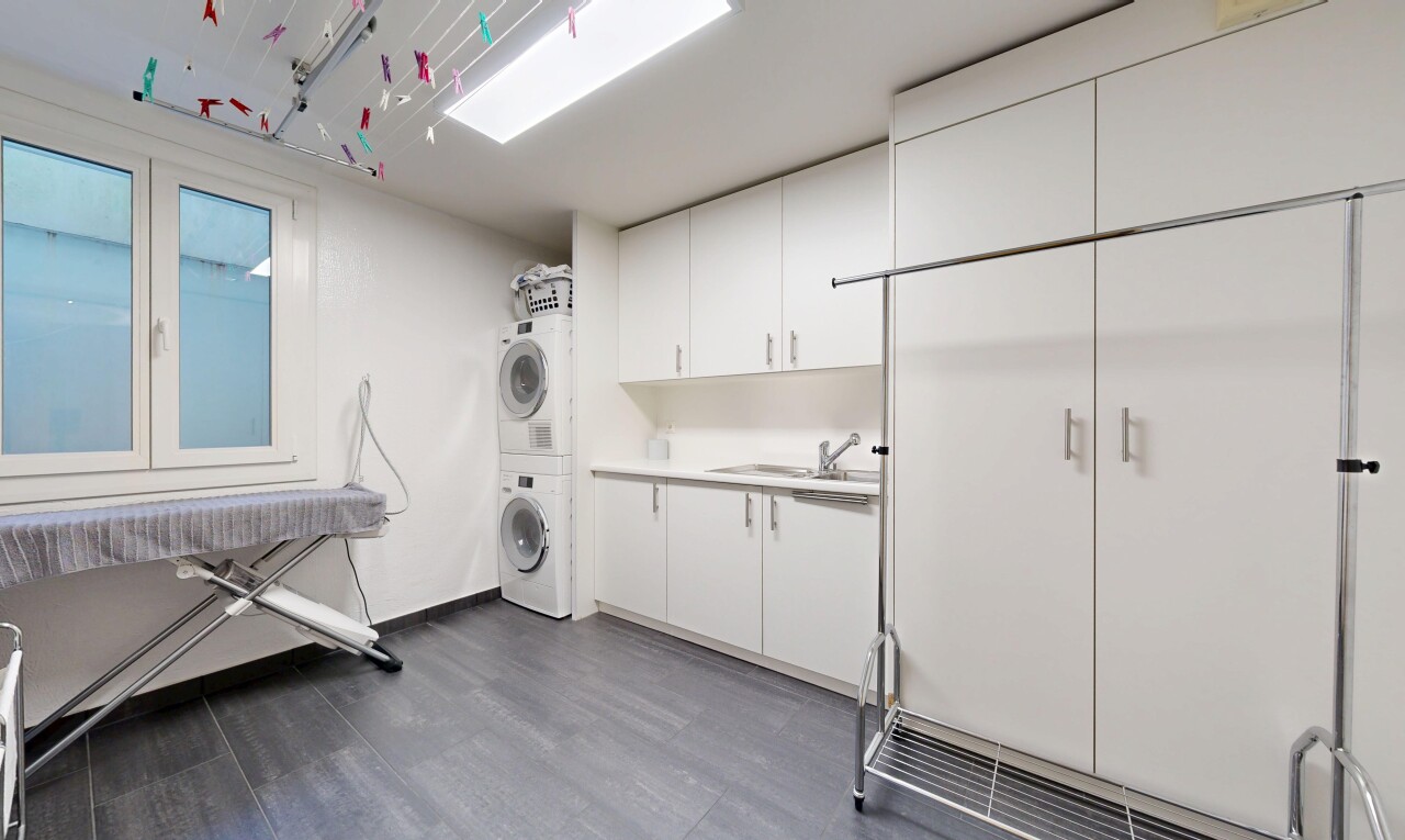 buanderie avec lave-linge et sèche-linge superposés, wood finish floor, sol en finition bois, buanderie, et dark floor