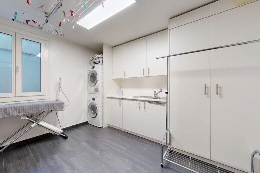 buanderie avec lave-linge et sèche-linge superposés, wood finish floor, sol en finition bois, buanderie, et dark floor