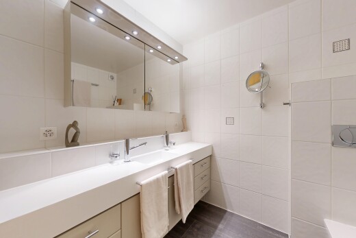 salle de bains avec lavabo (ou coiffeuse selon le contexte), mur en carrelage, tile wall, dark floor, et salle de bain complète