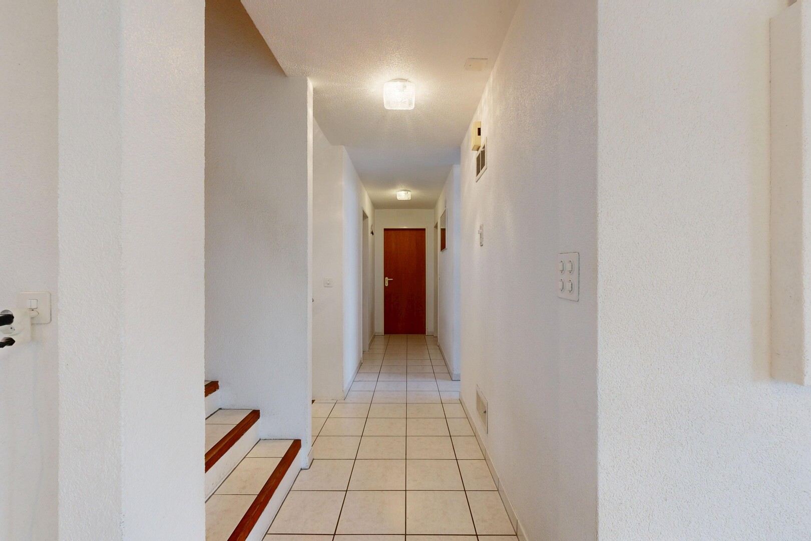 couloir avec tile floor, sol en carrelage, inside property, light floor, et drywall