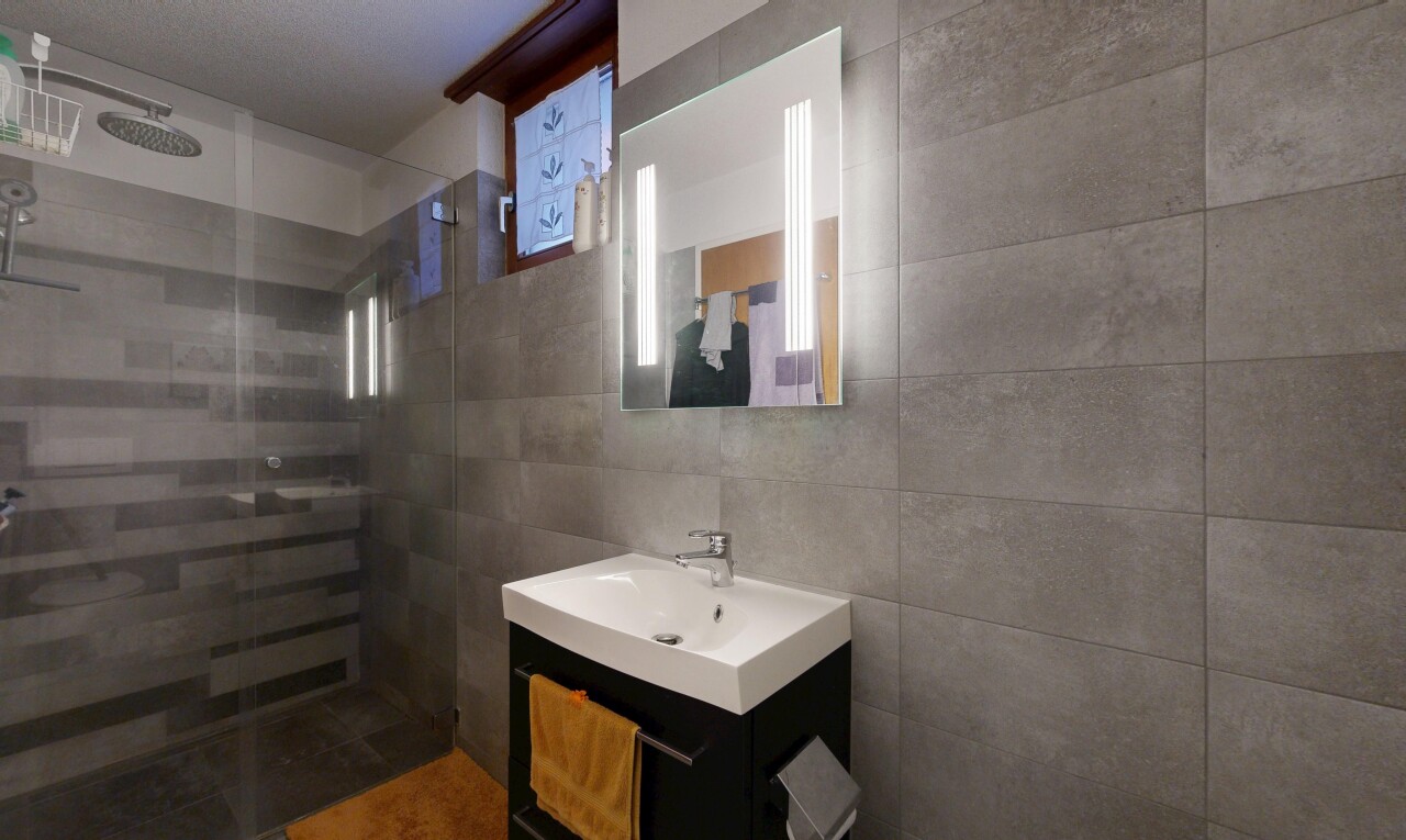 salle de bains avec lavabo (ou coiffeuse selon le contexte), douche, miroir, salle de bain complète, et tile wall