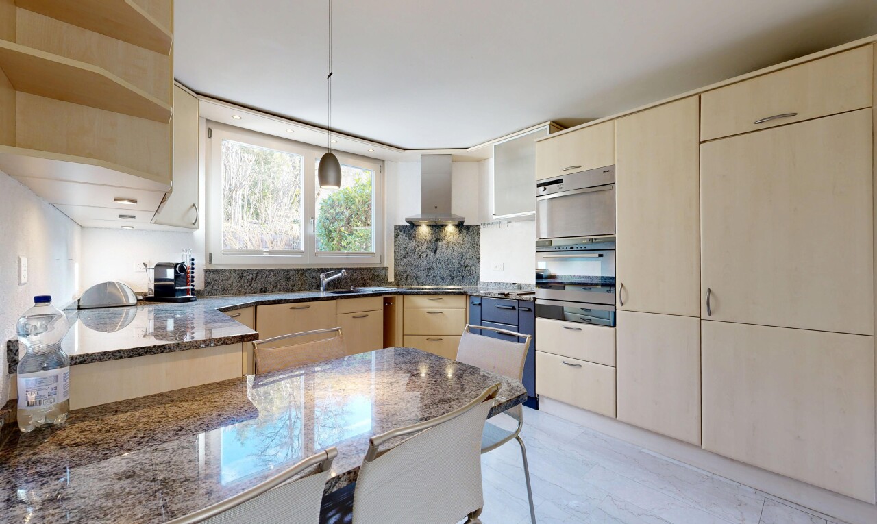 cuisine avec armoires marron clair, light brown cabinets, light floor, hotte, et plans de travail en pierre