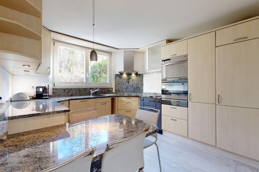 cuisine avec armoires marron clair, light brown cabinets, light floor, hotte, et plans de travail en pierre