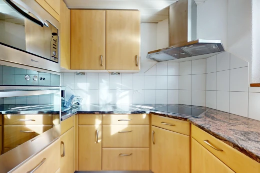 kitchen with stainless steel appliances, light brown cabinetry, ventilation hood, and decorative backsplash
