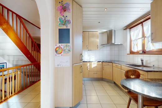 küche mit dunstabzugshaube, fliesenboden, hellbraune schränke, natürliches licht, und küchenrückwand beim herd