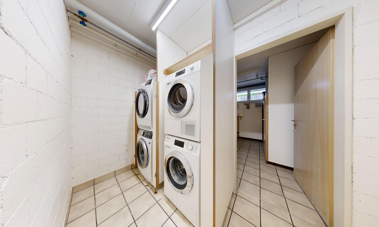 buanderie avec tile floor, light floor, lave-linge et sèche-linge superposés, sous-sol, et inside community