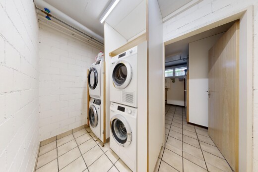buanderie avec tile floor, light floor, lave-linge et sèche-linge superposés, sous-sol, et inside community
