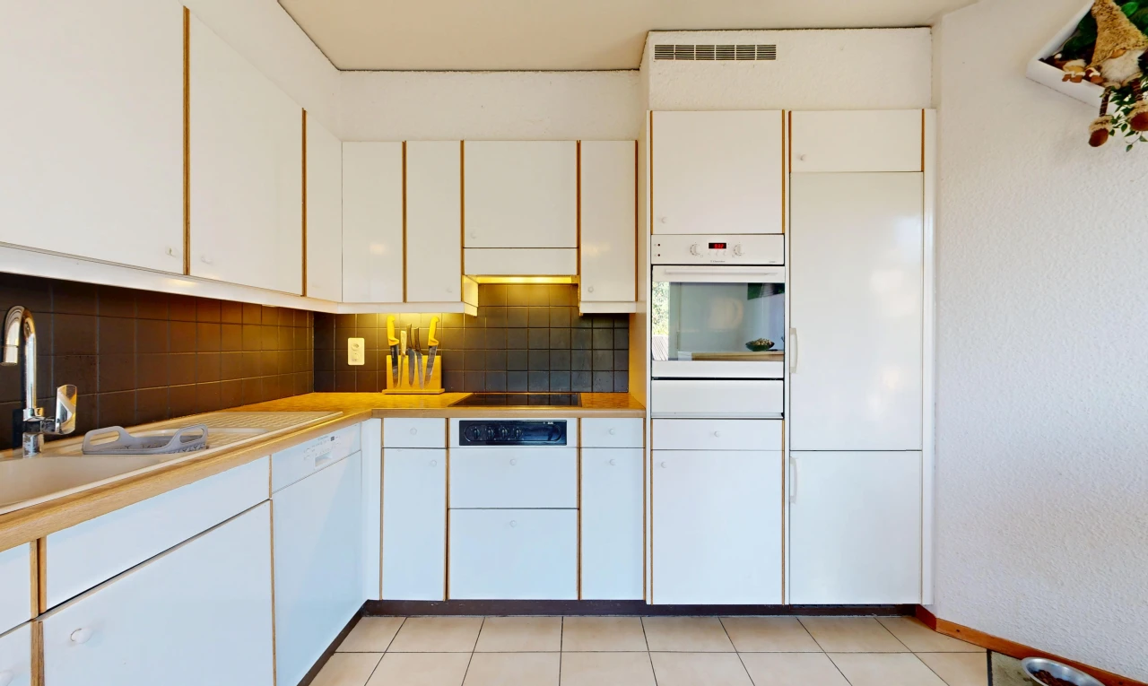 kitchen featuring white oven, white cabinets, light countertops, light tile patterned floors, and tasteful backsplash