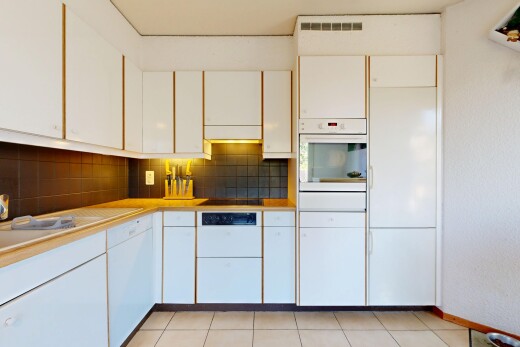 kitchen featuring white oven, white cabinets, light countertops, light tile patterned floors, and tasteful backsplash
