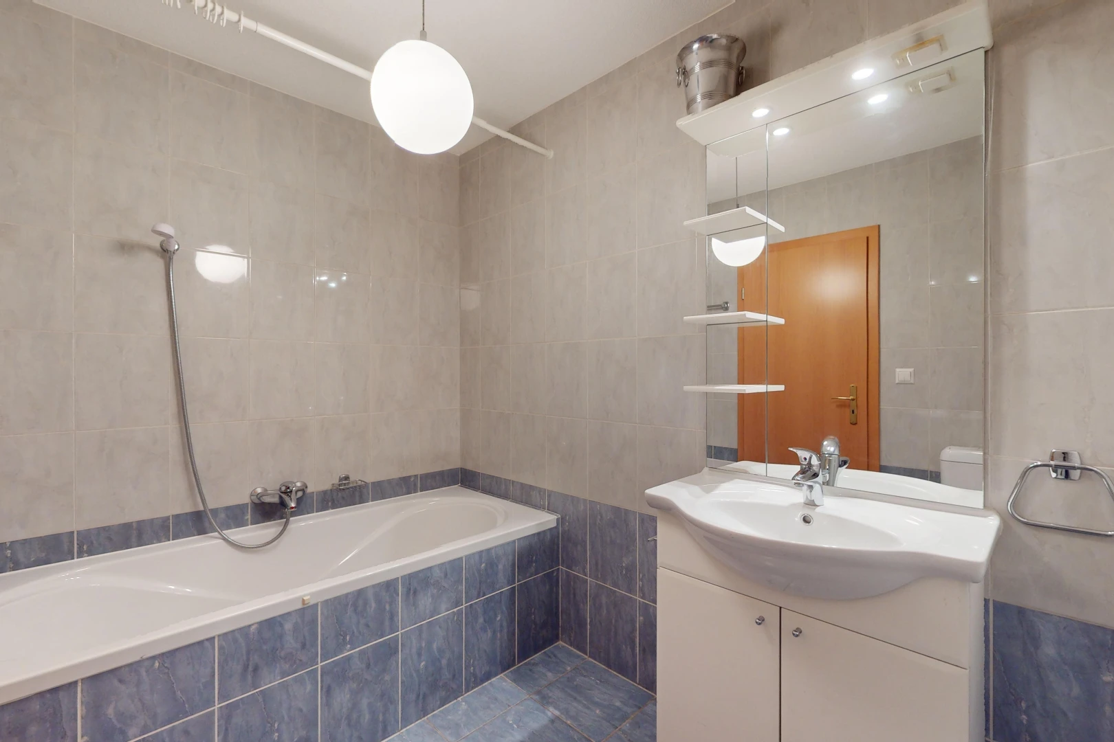 salle de bains avec bain-douche, mur carrelé, miroir, et meuble-lavabo