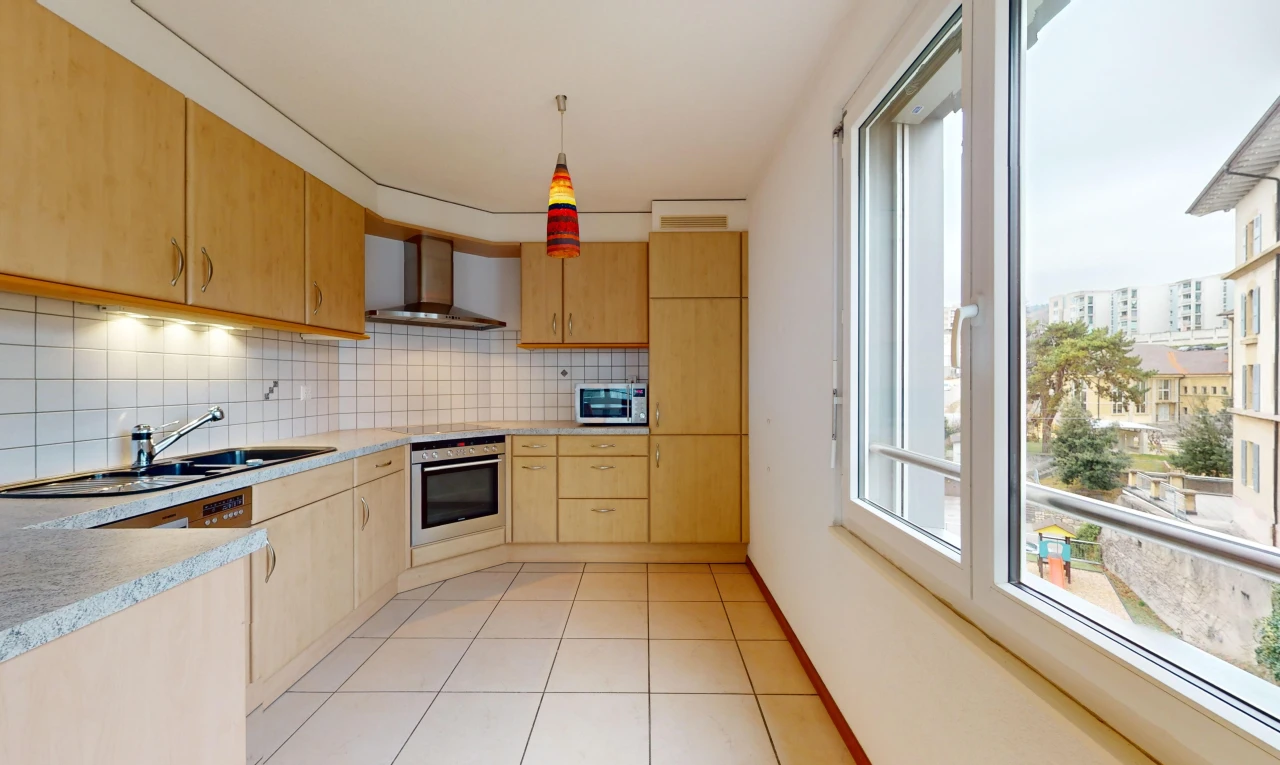 cuisine avec four, hotte, plan de travail, et lumière naturelle