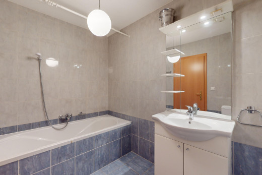 salle de bains avec bain-douche, mur carrelé, miroir, et meuble-lavabo