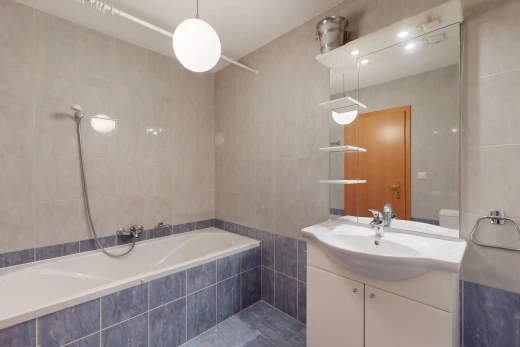 salle de bains avec bain-douche, mur carrelé, miroir, et meuble-lavabo
