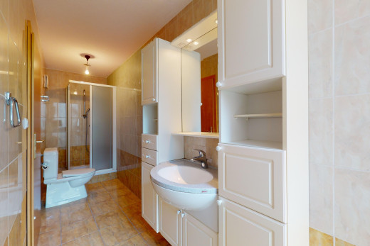 salle de bains avec mur carrelé, miroir, meuble-lavabo, et douche