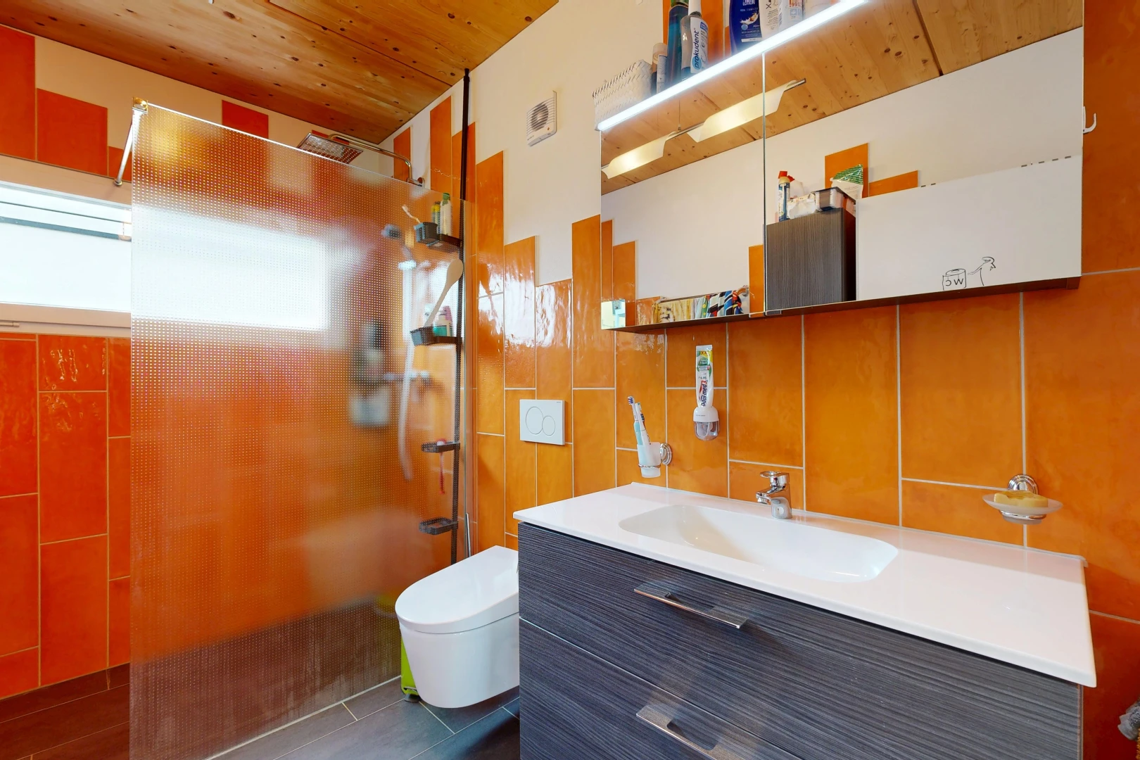 full bath with a tile shower, vanity, wood ceiling, and tile walls