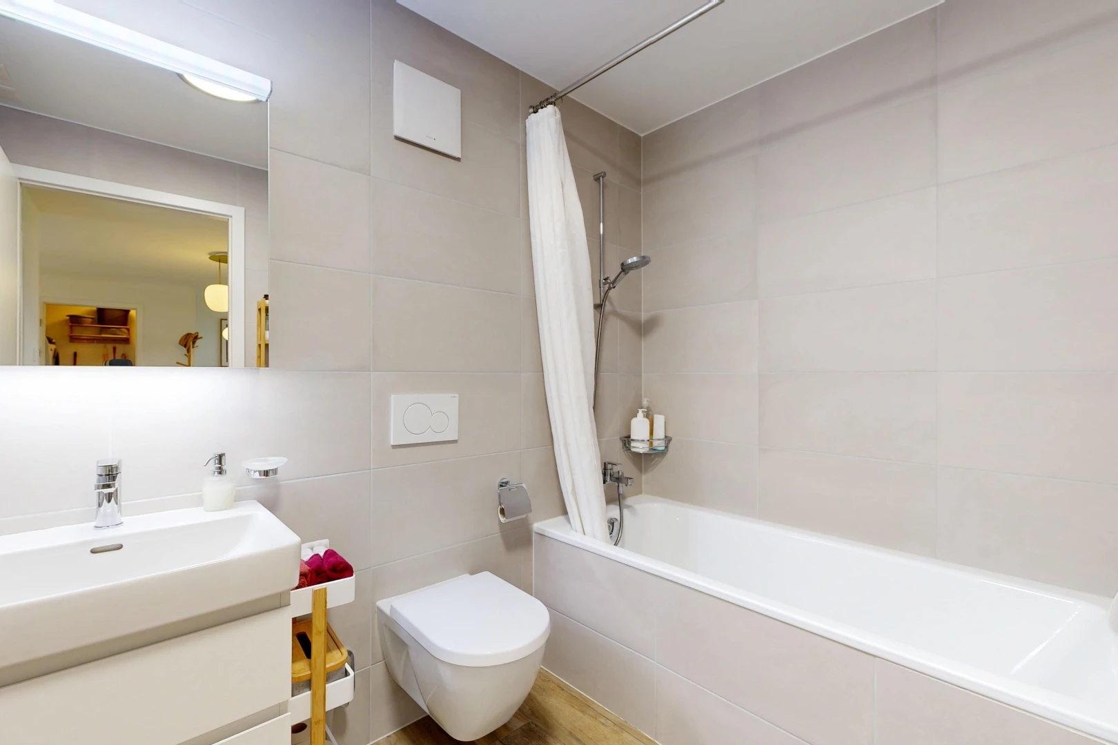 salle de bains avec douche-bain combinés, salle de bain complète, miroir, lavabo (ou coiffeuse selon le contexte), et mur en carrelage