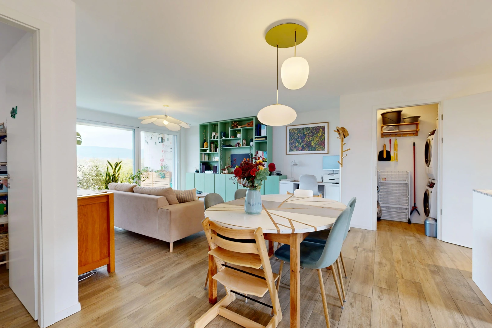salon / salle à manger avec étagères intégrées, lave-linge et sèche-linge superposés, sol en finition bois, wood finish floor, et cloison sèche