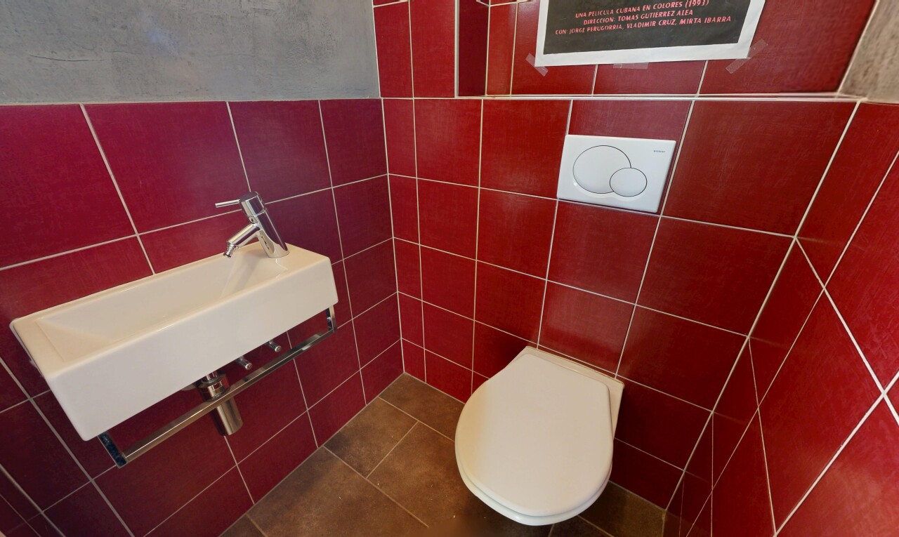 salle de bains avec toilette, tile wall, évier, et inside community