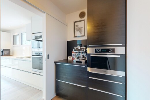 kitchen with modern cabinets, white cabinets, light countertops, double oven, and black microwave