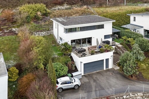 façade avec property visible, bardage en stuc, allée, garage intégré, et clôture