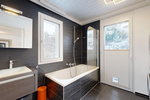bathroom with vanity, tiled shower / bath, dark tile patterned flooring, and tile walls