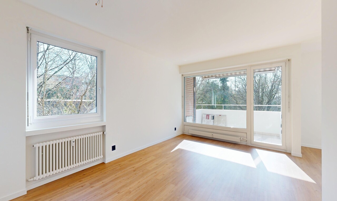 spare room featuring radiator heating unit, light wood-type flooring, plenty of natural light, and a baseboard heating unit