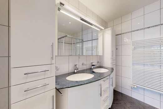full bathroom with double vanity, radiator, a towel warming rack, tile walls, and a shower stall