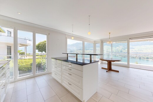 kitchen with white cabinetry, hanging light fixtures, a kitchen island, crown molding, and expansive windows