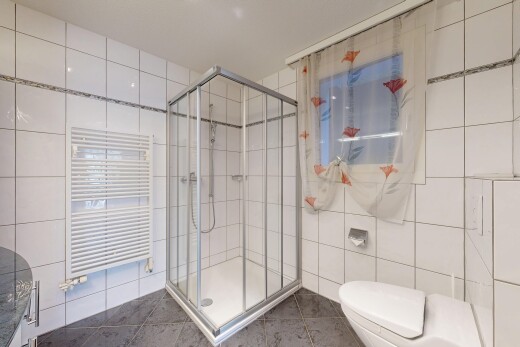 bathroom featuring a towel warming rack, tile walls, a shower stall, radiator heating unit, and dark tile patterned floors