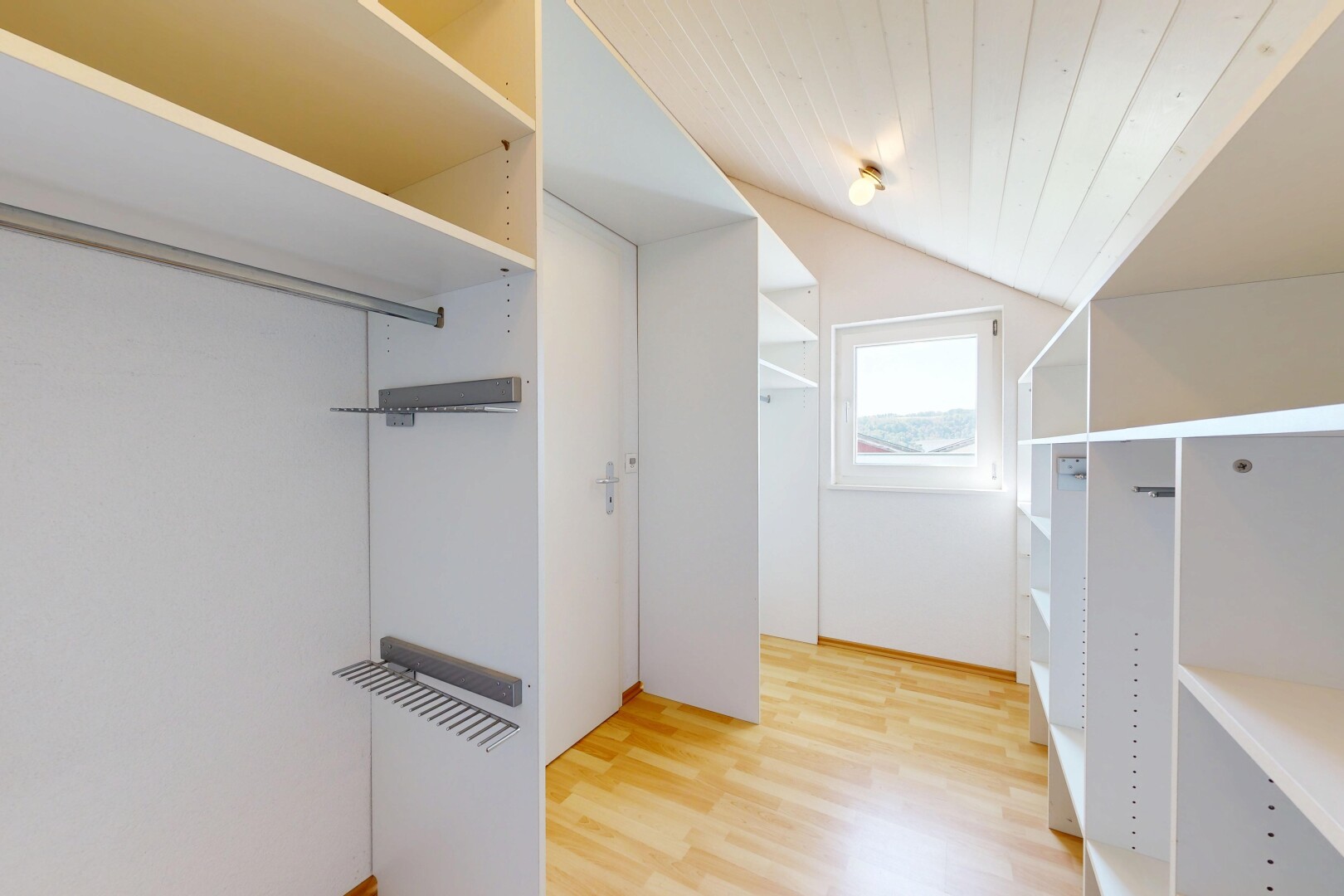 begehbarer kleiderschrank mit natürliches licht, begehbarer kleiderschrank, vaulted ceiling, dachschräge, und wood finish floor