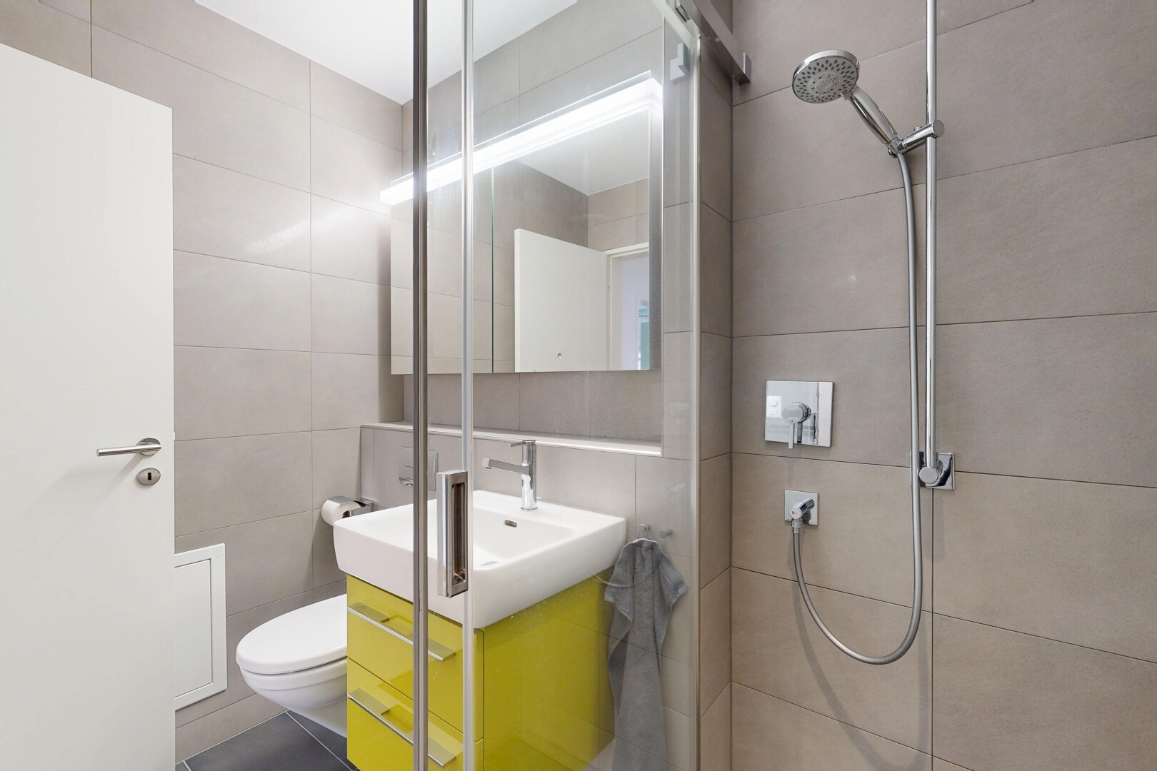 salle de bains avec tile wall, mur en carrelage, miroir, lavabo (ou coiffeuse selon le contexte), et douche
