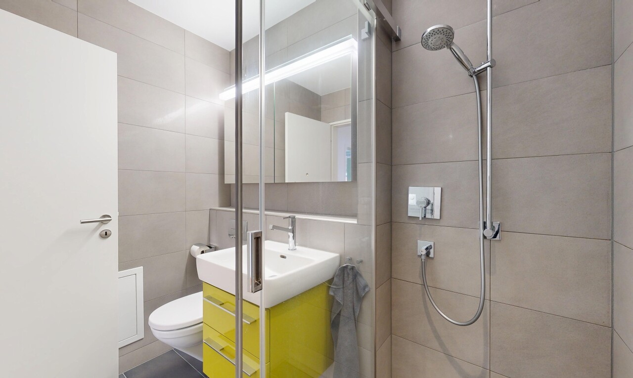 salle de bains avec tile wall, mur en carrelage, miroir, lavabo (ou coiffeuse selon le contexte), et douche