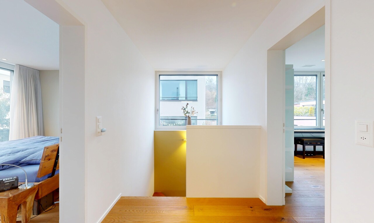 couloir avec wood finish floor, sol en finition bois, drywall, cloison sèche, et natural light