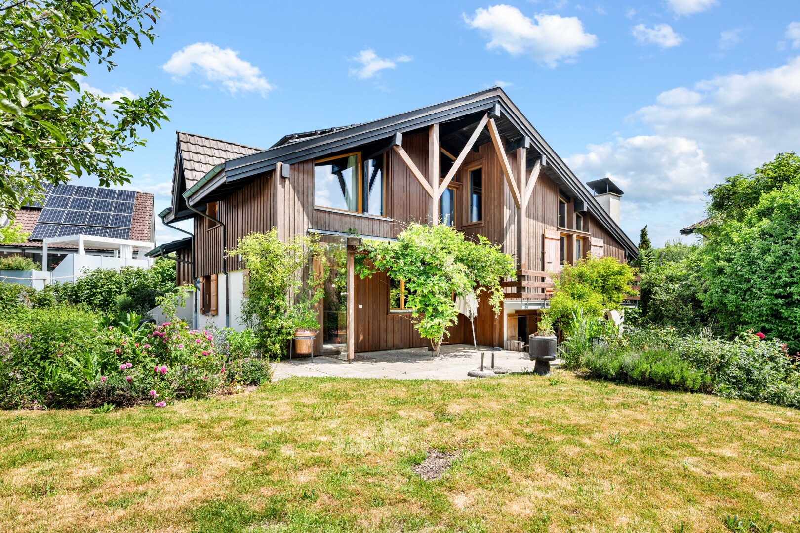 außenansicht mit vertikale verkleidung, rasen, terrasse, property visible, und day time