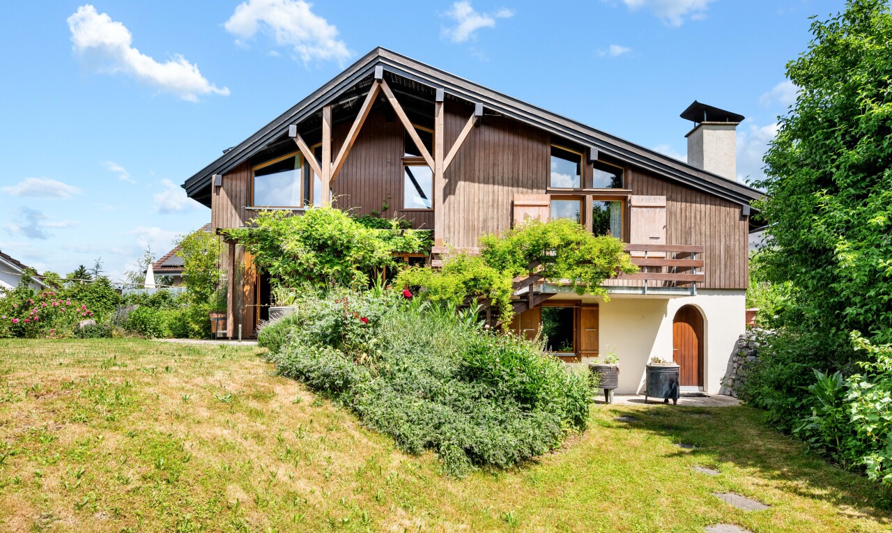 view of property featuring a lawn, a chimney, and a balcony