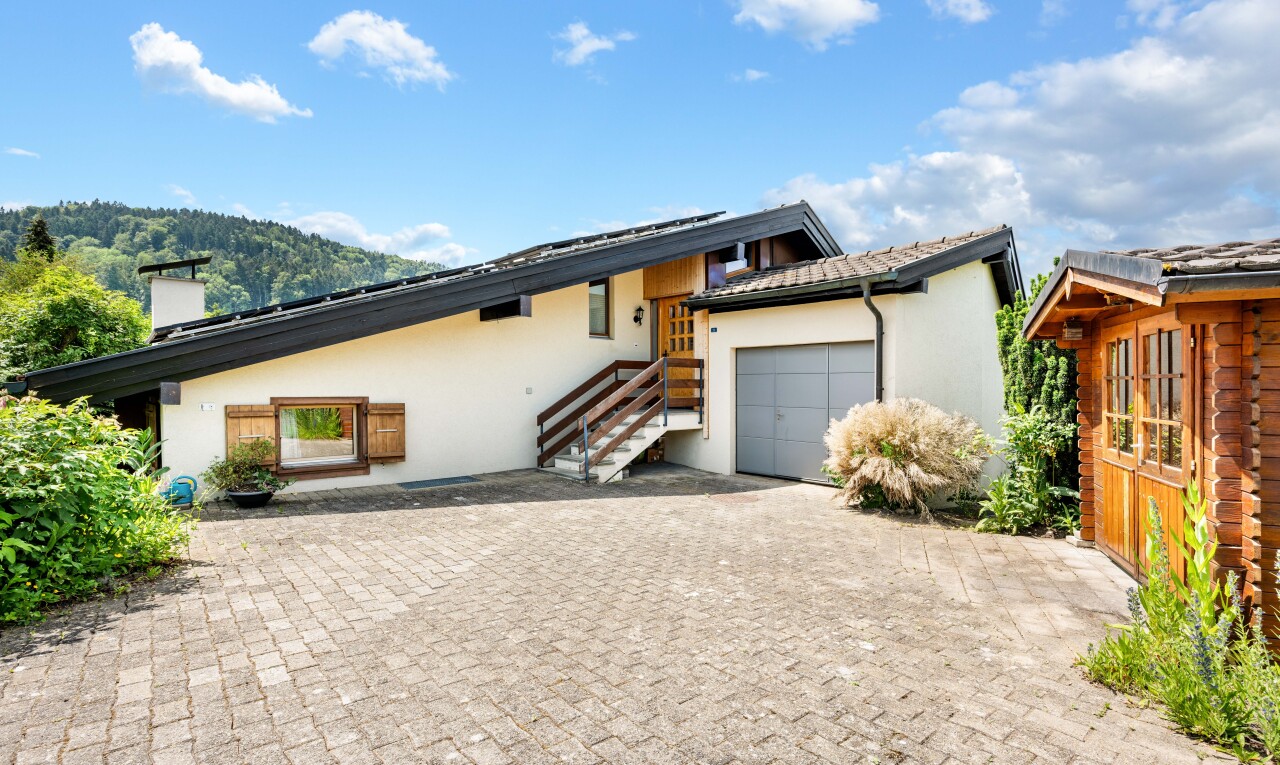 view of home featuring stucco siding, an attached garage, a chimney, and decorative driveway