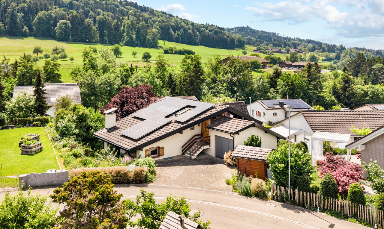 view of home featuring solar panels, a chimney, driveway, and stucco siding