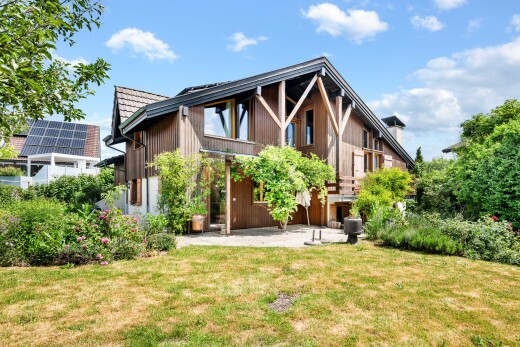 außenansicht mit vertikale verkleidung, rasen, terrasse, property visible, und day time
