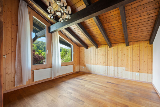 leerer raum mit balkendecke, beamed ceiling, bemerkenswerter kronleuchter, inside property, und holzfußboden