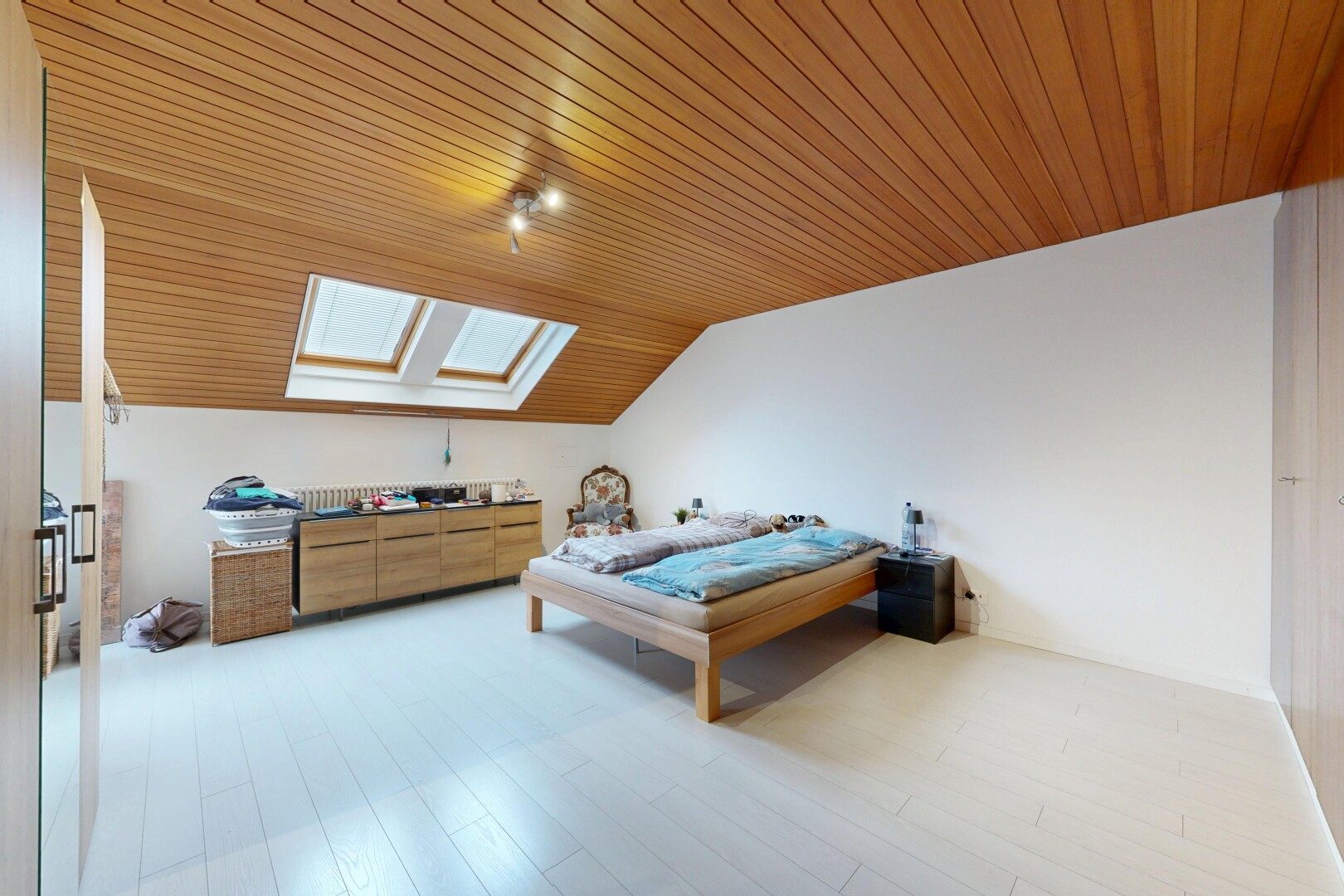 room / bedroom featuring a skylight, vaulted ceiling, wood ceiling, and light wood-type flooring
