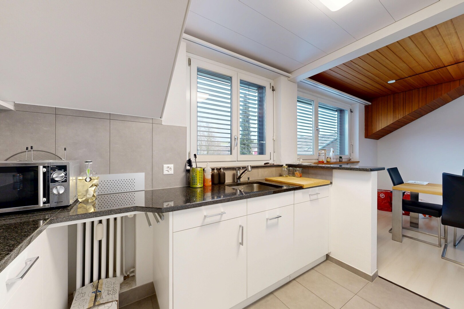kitchen featuring backsplash, white cabinetry, stainless steel microwave, and light tile patterned floors